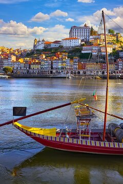 Old town of Porto, Portugal. Antique boat with port wine barrels on the water Douro River. Sunny day over silhouettes skyline roofs houses along river.
