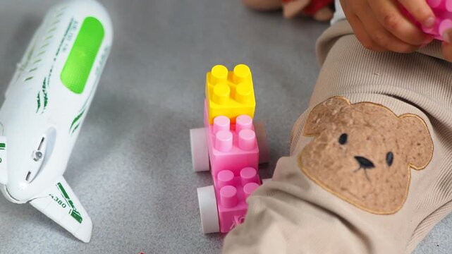 Child's Hands Playing with Colorful Building Blocks and Toy Airplane