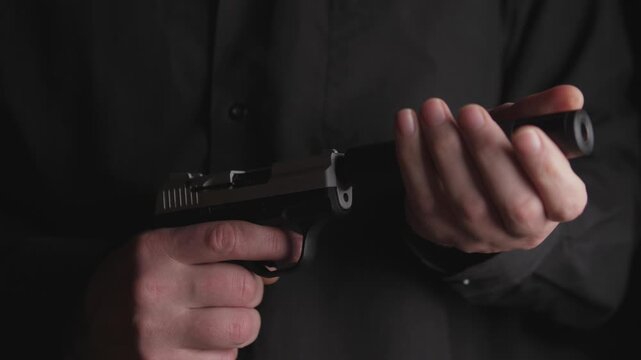 The killer turns on the silencer for silent shooting on his gun