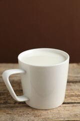 Fresh milk in mug on wooden table