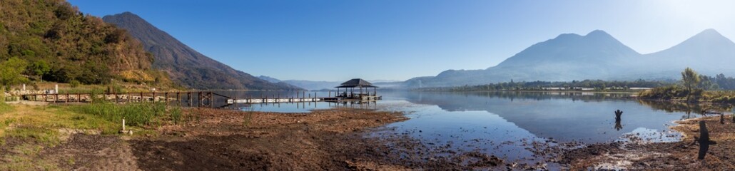 Serene lake with wooden dock and mountains in the background
