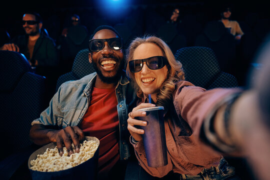 Happy couple taking selfie while watching 3D movie in cinema.