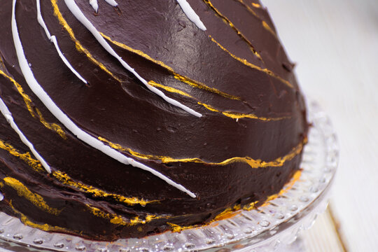 An elegant chocolate Christmas bombe cake with gold leaf accents, white chocolate drizzle, 