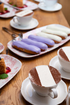 Eclairs and cappuccino on a table in a restaurant. French dessert.