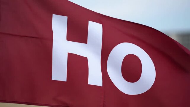 Close up of a maroon flag with white letters HO waving in the wind.