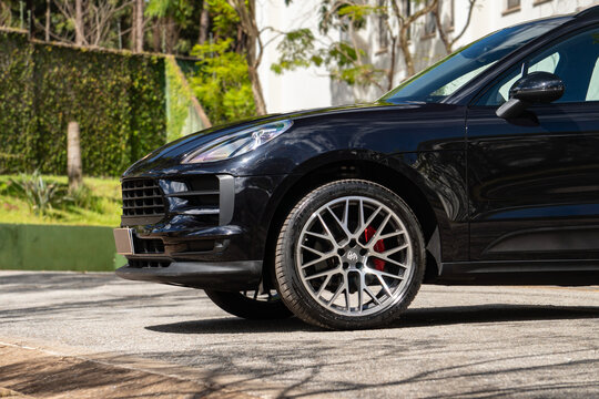 Black Porsche Macan front end side profile, Luxury SUV parked outdoors on sun light