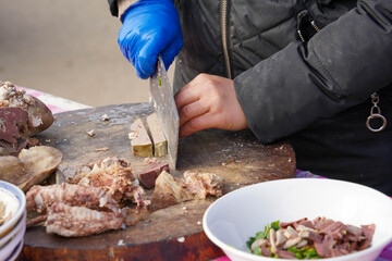 Chef Slicing Cooked Meat on a Wooden Cutting Board for a Street Food Dish