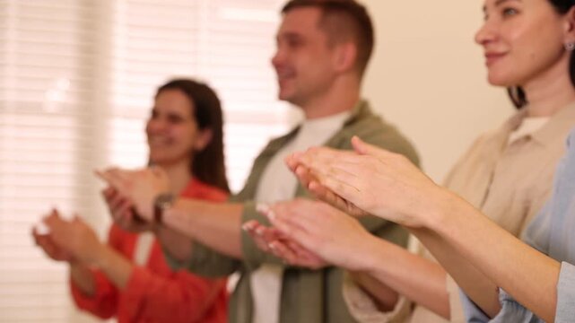 Group of people clapping hands indoors, selective focus