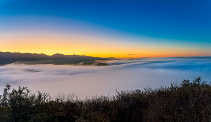 Obraz premium Panorama of cloud inversion over valley and mountains, at sunset
