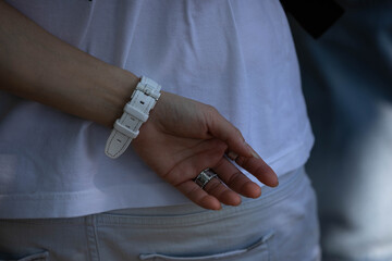 Hand of man with rings and white watch resting behind back, alone in crowd, solitary person in busy street, close up, at Chatuchak Market.