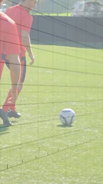 Vertical video: Red soccer player taking ball to keep control dribbling on turf as rival pressing