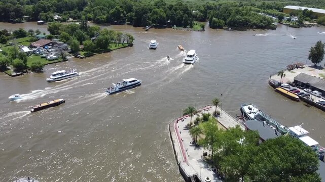 Traffic of wooden boats, catamarans, and motorboats departing from the Puerto de Frutos in Tigre towards the Lujan River on a sunny day.