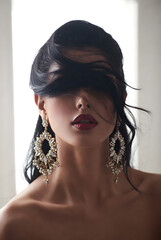 Elegant Fashion Portrait of Woman with Dramatic Hair and Ornate Statement Earrings