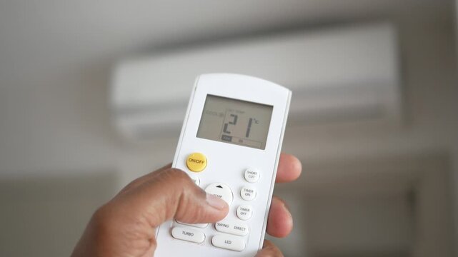 Close up video of person holding air conditioner remote control and adjusting temperature to cooler setting