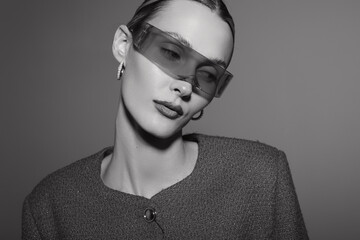 Caucasian woman with light skin wearing modern sunglasses and hoop earrings poses with closed eyes in studio. Concept of fashion, style, elegance, and minimalism in black and white. © SHOTPRIME STUDIO