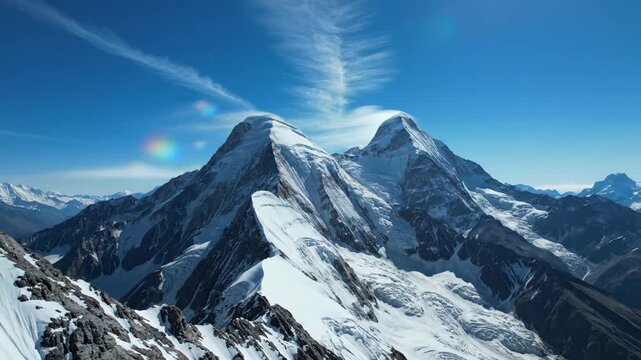 Majestic snow-capped mountain peaks with wispy cirrus clouds under a bright blue sky, showcasing nature's grandeur.