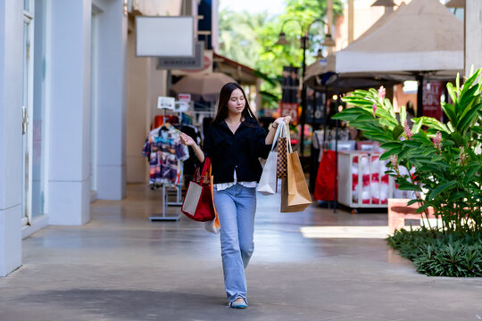 Young Woman Walking Confidently While Carrying Shopping Bags in Outdoor Mall