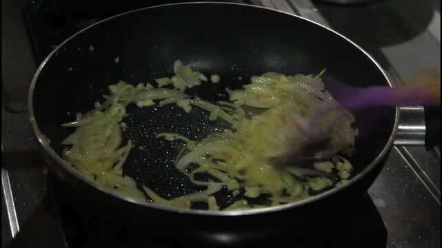 Saut&eacute;ing Sliced Onions and Garlic in Hot Pan with Blue Gas Flame