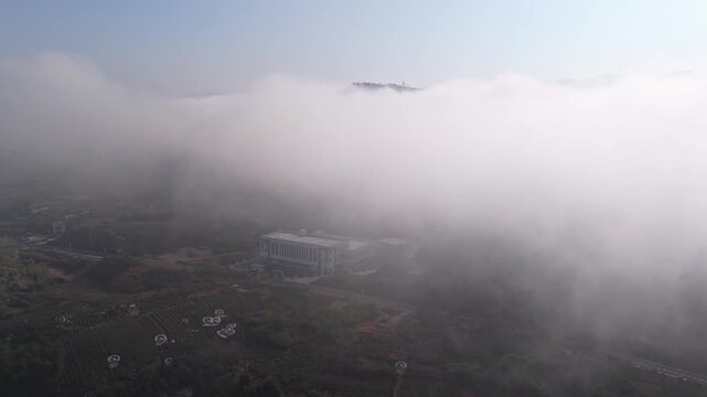 An aerial view of the building shrouded in clouds and mist