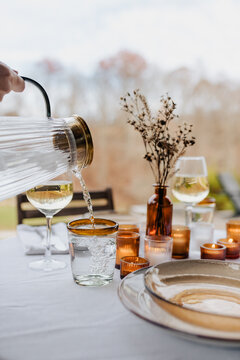 Pouring water in a glass for a nice dinner on the patio in the fall.