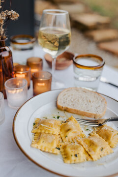 Butternut squash ravioli with brown butter sauce for dinner on a patio.