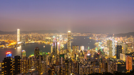 Fototapeta premium Panoramic night skyline of a modern coastal financial city with illuminated skyscrapers and harbor lights. 