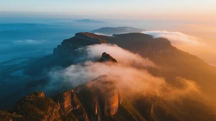 Fototapeta premium Aerial view of mountain peaks emerging from clouds at sunrise