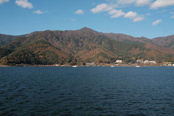 Fototapeta premium Mountain range across Lake Kawaguchiko under blue sky with clouds