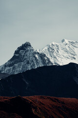 Obraz premium Snowy mountains rise above dark hills in South Georgia Island on a cloudy day with no signs of wildlife visible