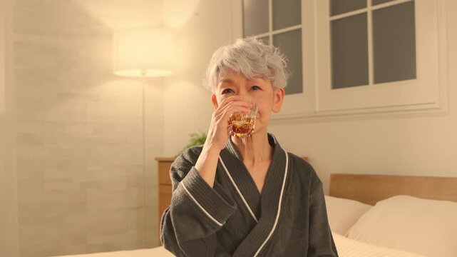 ガウンコート姿でロックグラスを持つシニア女性　ライフスタイルイメージ	
