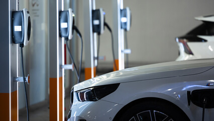 Naklejka premium EV charging and electric car, Electric car charging station for charge EV battery, Plug for vehicle with electric engine, EV charger clean energy, Charging point at car parking lot