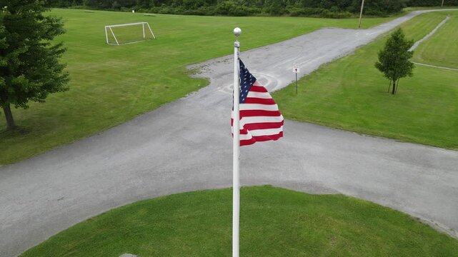 Low angle view of the United States flag waving on a pole against a clear blue sky.
