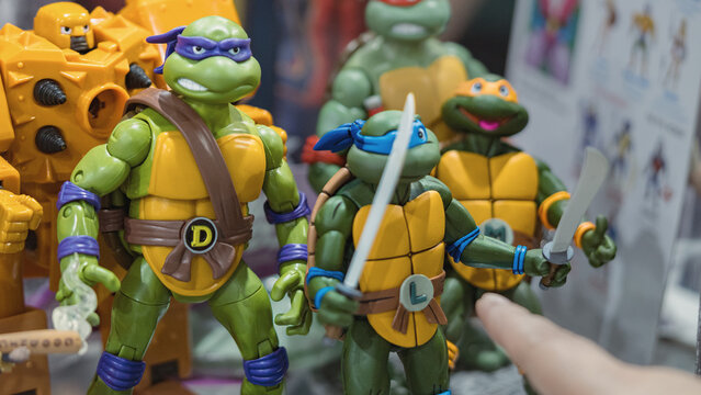 GUAYAQUIL, ECUADOR &ndash; AUG 06, 2023: Teenage Mutant Ninja Turtles action figures displayed at a pop culture collectibles stand while a visitor points at the toys during a Comic Con event