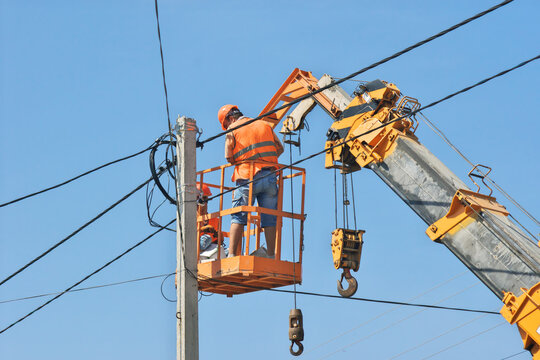 Electricians repairing power lines from an aerial lift platform