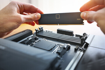 Obraz premium Technician installing high-speed DDR5 RAM into a computer motherboard
