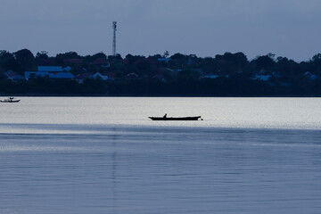 Obraz premium close up silhouette of a fisherman in a boat fishing in the sea. evening atmosphere with golden color. beautiful view suitable for wallpaper or background