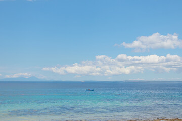 Fototapeta premium beautiful view of the beach and tropical blue sea during the day with the background of islands and clouds on daylight. beautiful view suitable for wallpaper or background