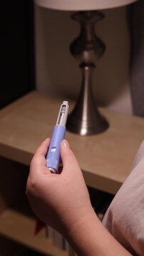 A vertical close up of a young woman screws a needle on pre-filled pen injector to prepare it for taking medicine
