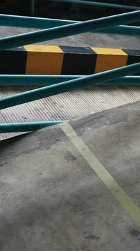 Close-up of a metal barrier with a black and yellow pattern on a concrete floor in a parking garage