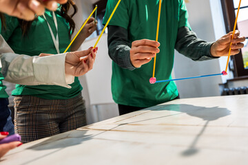 Hands building eco house model from plastic straws