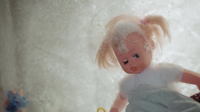 Rescuer gently retrieves. Tender person recovers icy doll. Kind helper finds frozen toy amid debris. Compassionate responder carefully retrieves frostcovered doll from ruins with gentle touch