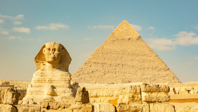 Sphinx and pyramid stand together in Giza under a clear sky during daylight hours