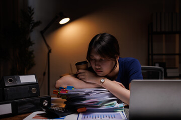 Exhausted business woman having headache after hard working day sitting in office late at night in...