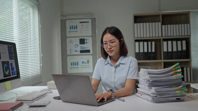 Asian businesswoman typing on laptop at office desk