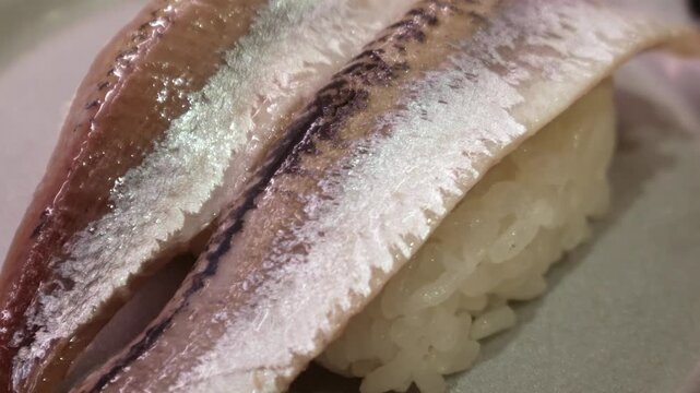 Fresh whole sardine or iwashi nigiri sushi two pieces on ceramic plate with shiny silver skin, Japanese restaurant