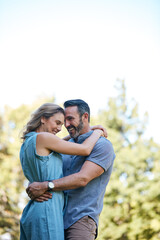 Fototapeta premium Happy, hug and couple in nature for love, care and bonding in marriage at park by space. Smile, outdoor and man embracing woman for trust, safety and connection in relationship at countryside.