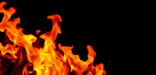 Fototapeta premium Intense orange and yellow flames burning against a black background, bright, inferno