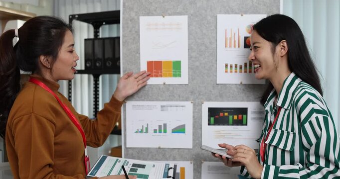 Two businesswomen discussing startup ideas and reviewing documents during a meeting in modern office, representing teamwork, business planning and collaboration in a startup company.
