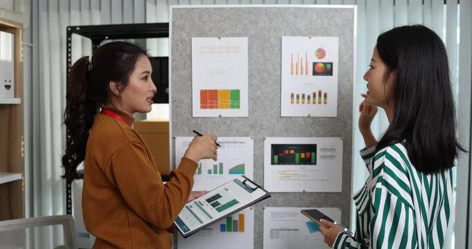 Two businesswomen discussing startup ideas and reviewing documents during a meeting in modern office, representing teamwork, business planning and collaboration in a startup company.