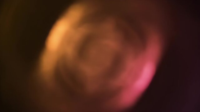 Blurry, abstract image with a circular gradient of orange, brown and pink hues